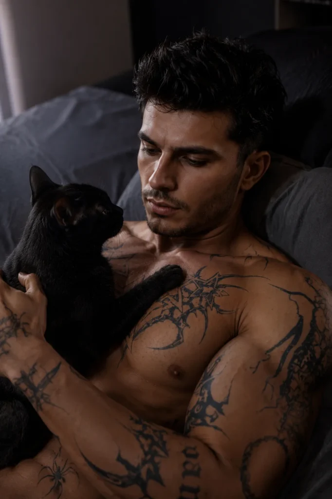 Homem tatuado com gato preto em cena intimista com iluminação cinematográfica azulada e estética fotorealista editorial.